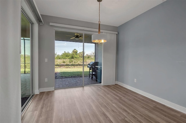 unfurnished dining area with ceiling fan, wood finished floors, and baseboards