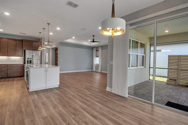 kitchen featuring light countertops, visible vents, high quality fridge, and light wood finished floors