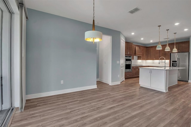 kitchen featuring stainless steel appliances, light countertops, visible vents, light wood-style floors, and baseboards