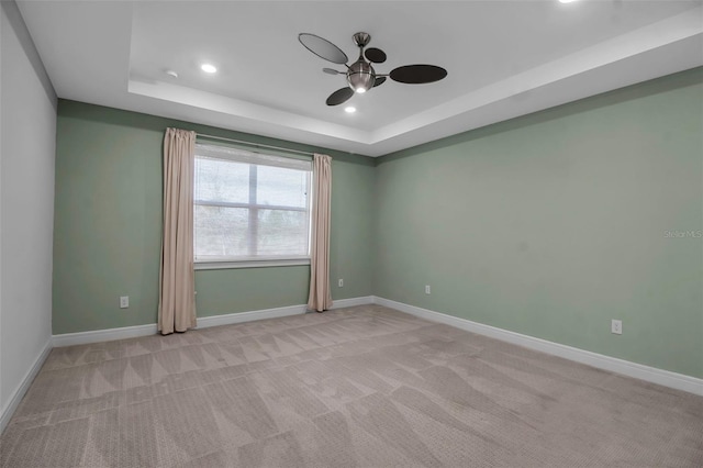 spare room featuring light carpet, baseboards, a ceiling fan, a tray ceiling, and recessed lighting