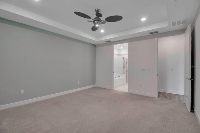 unfurnished bedroom featuring a tray ceiling, visible vents, light carpet, and recessed lighting