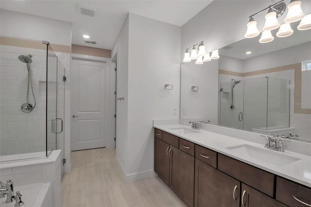 full bathroom featuring double vanity, a stall shower, baseboards, and a sink