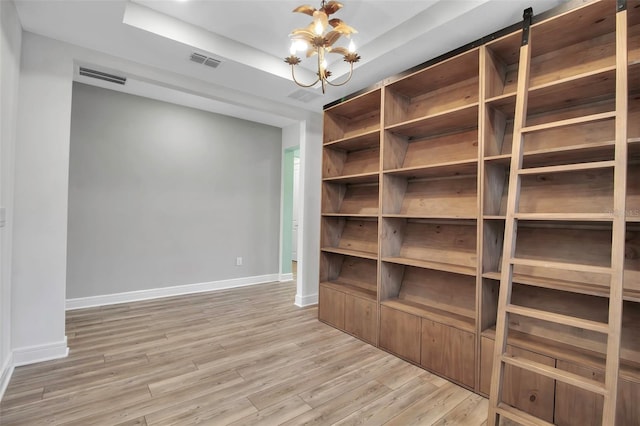 unfurnished room with light wood-type flooring, a tray ceiling, visible vents, and baseboards