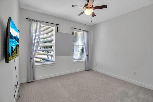 carpeted spare room with ceiling fan and baseboards