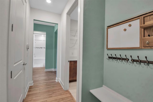 hall with light wood-style flooring and baseboards