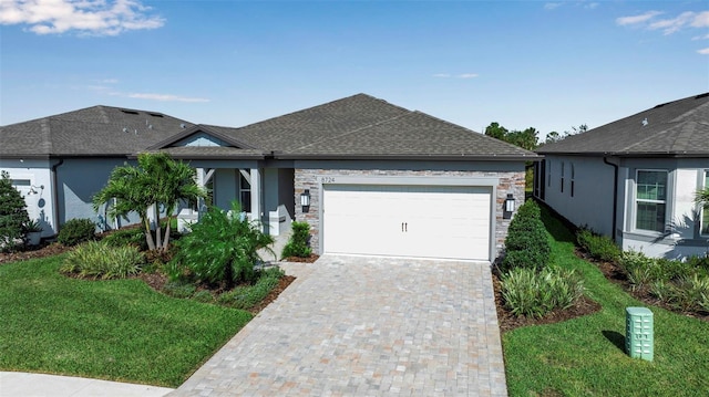 ranch-style house with a garage, stone siding, roof with shingles, decorative driveway, and a front lawn