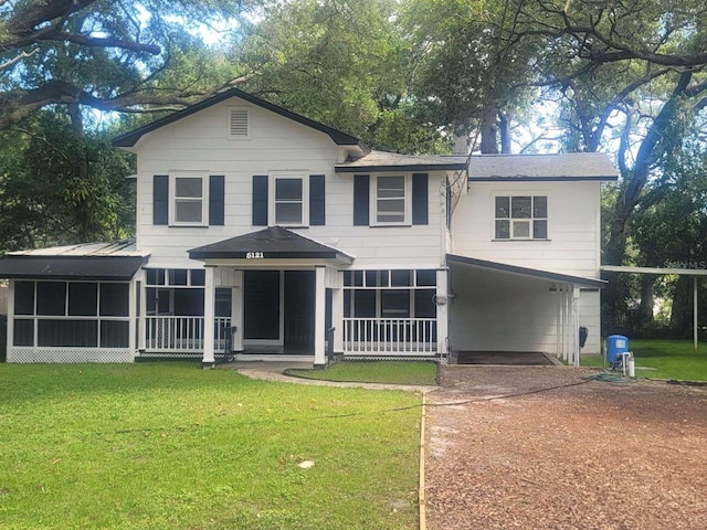 traditional-style house with a carport, a sunroom, driveway, and a front lawn