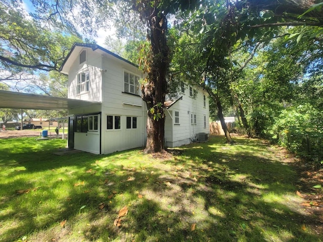 exterior space with a carport, cooling unit, and a yard