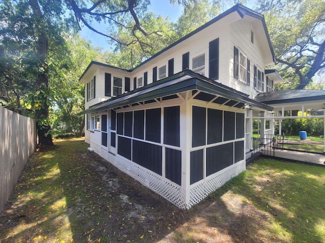 view of side of home featuring a sunroom and fence