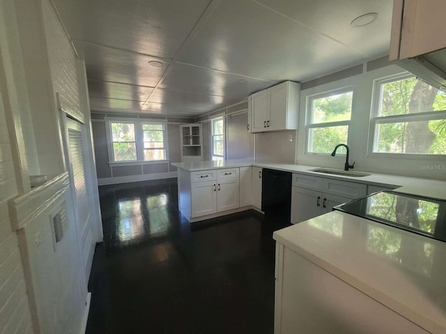 kitchen featuring black dishwasher, dark wood-type flooring, white cabinets, a sink, and a peninsula