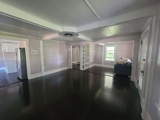 spare room with dark wood-type flooring, visible vents, and baseboards