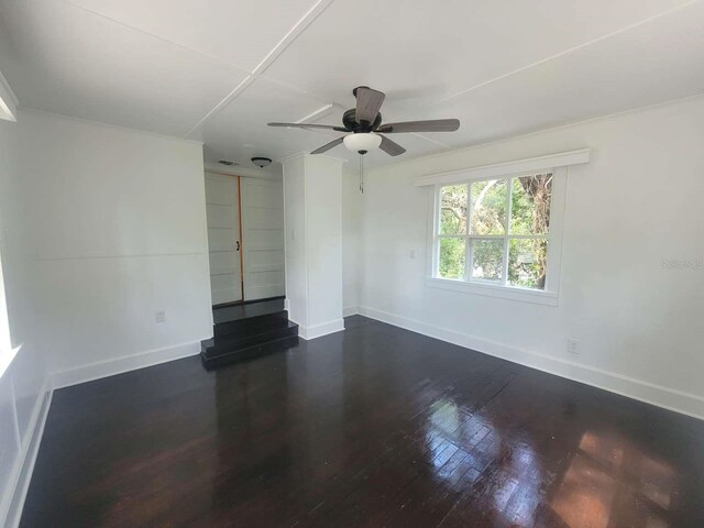 spare room featuring dark wood finished floors, a ceiling fan, and baseboards