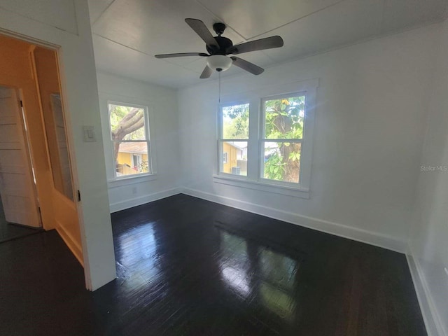 unfurnished room featuring dark wood finished floors, a ceiling fan, and baseboards