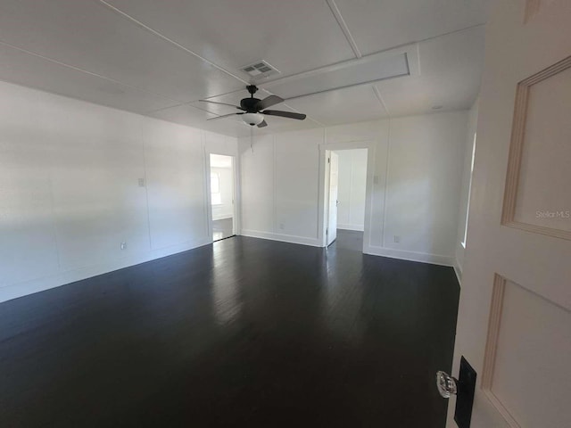 unfurnished room with ceiling fan, dark wood-type flooring, visible vents, baseboards, and attic access