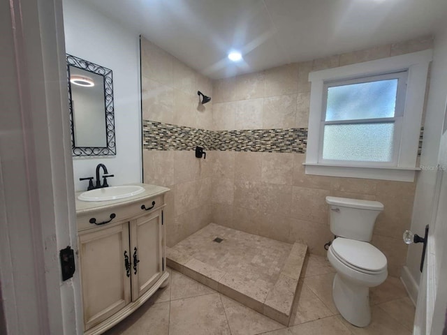 bathroom with a tile shower, vanity, toilet, and tile patterned floors