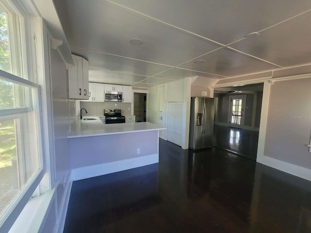 kitchen featuring white cabinets, a peninsula, stainless steel appliances, light countertops, and a sink