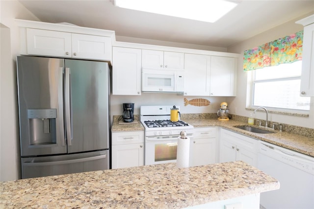 kitchen featuring light stone counters, white appliances, white cabinets, and a sink