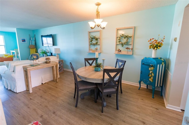 dining space with a notable chandelier, baseboards, and wood finished floors