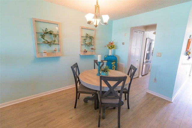 dining space featuring light wood-type flooring, a notable chandelier, and baseboards