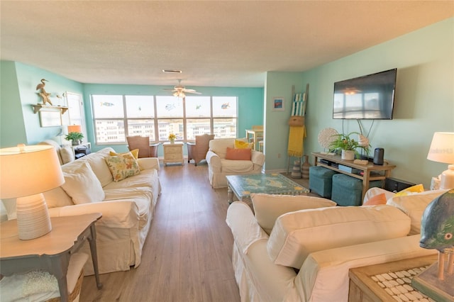 living room with a textured ceiling, wood finished floors, and a ceiling fan