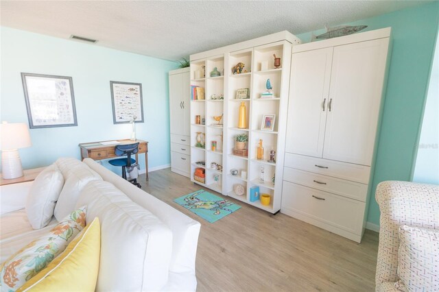 game room featuring a textured ceiling, light wood finished floors, visible vents, and baseboards