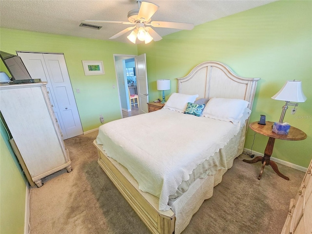 carpeted bedroom featuring a closet, visible vents, a ceiling fan, a textured ceiling, and baseboards