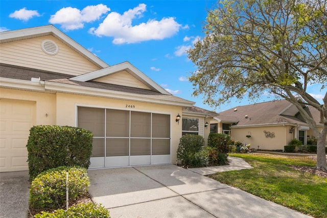 view of front of property featuring stucco siding, a shingled roof, concrete driveway, a garage, and a front lawn