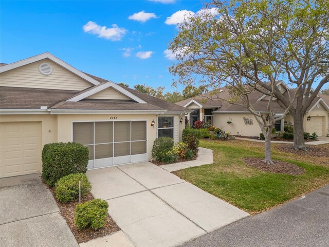 ranch-style home with stucco siding, a shingled roof, an attached garage, driveway, and a front lawn