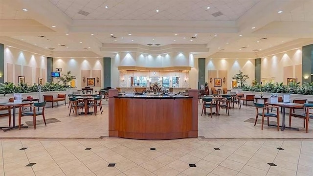 interior space with a tray ceiling, light tile patterned flooring, dark countertops, and a high ceiling