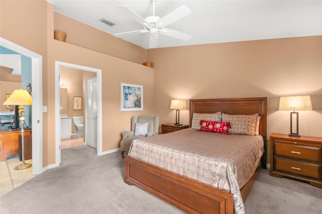 bedroom with ceiling fan, light carpet, visible vents, baseboards, and ensuite bath