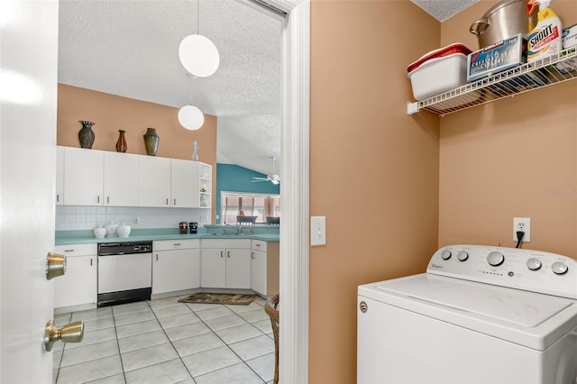 washroom with a textured ceiling, light tile patterned flooring, laundry area, a sink, and washer / clothes dryer