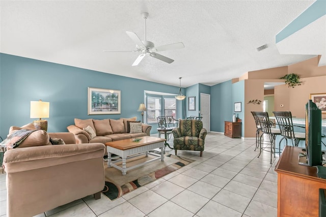 living area with lofted ceiling, a textured ceiling, light tile patterned flooring, and visible vents