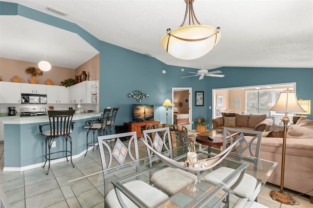 living room featuring light tile patterned floors, a textured ceiling, visible vents, a ceiling fan, and vaulted ceiling