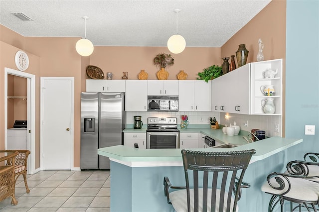 kitchen featuring decorative light fixtures, backsplash, appliances with stainless steel finishes, light tile patterned flooring, and a peninsula