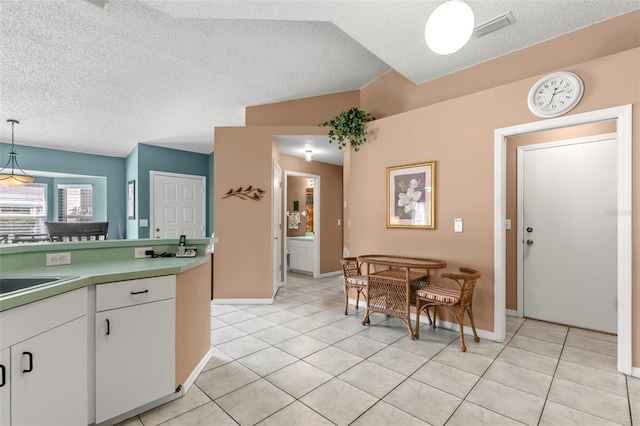 kitchen featuring decorative light fixtures, light tile patterned floors, visible vents, white cabinets, and a textured ceiling