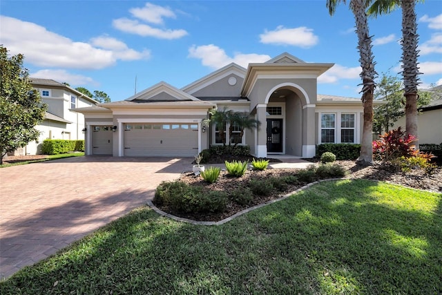 view of front of home with an attached garage, a front yard, decorative driveway, and stucco siding