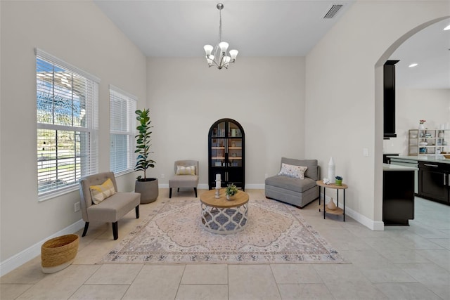 sitting room with arched walkways, a notable chandelier, light tile patterned floors, visible vents, and baseboards