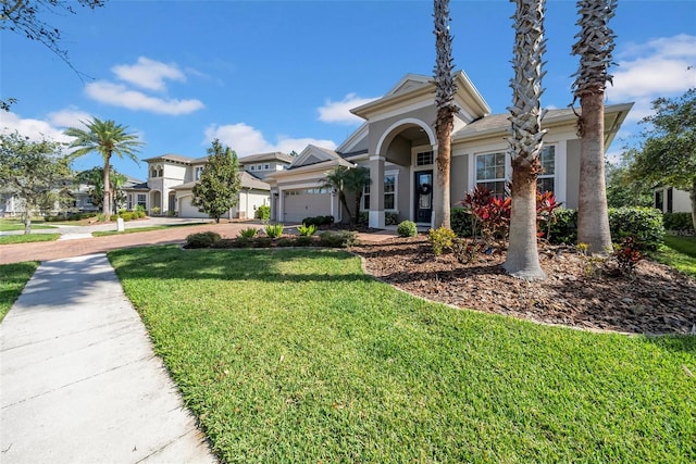 view of front facade featuring stucco siding, an attached garage, a front yard, a residential view, and driveway