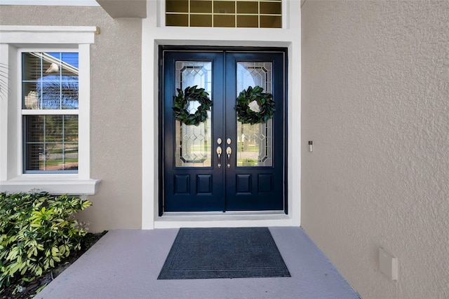 property entrance with stucco siding and french doors