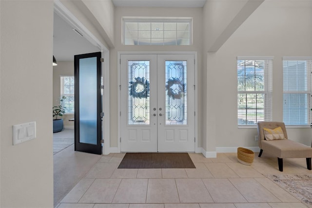 tiled entrance foyer featuring arched walkways, french doors, a high ceiling, and baseboards