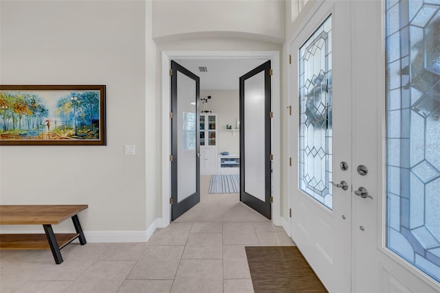 entryway featuring light tile patterned floors, visible vents, a wealth of natural light, and baseboards