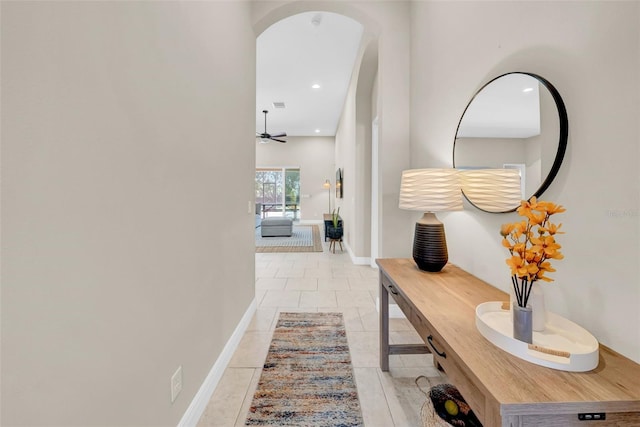 corridor with light tile patterned floors, baseboards, visible vents, arched walkways, and recessed lighting