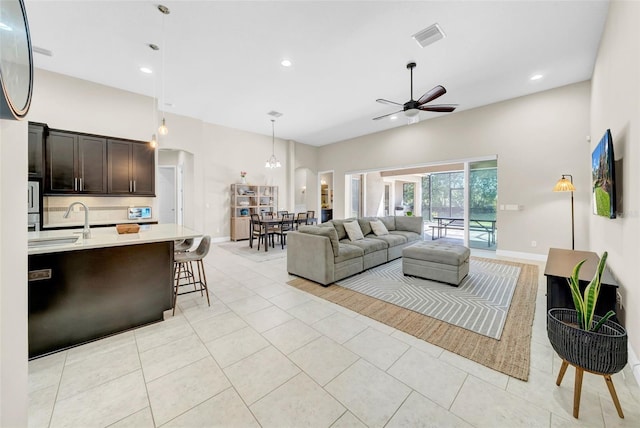 living area with a ceiling fan, visible vents, baseboards, and light tile patterned flooring