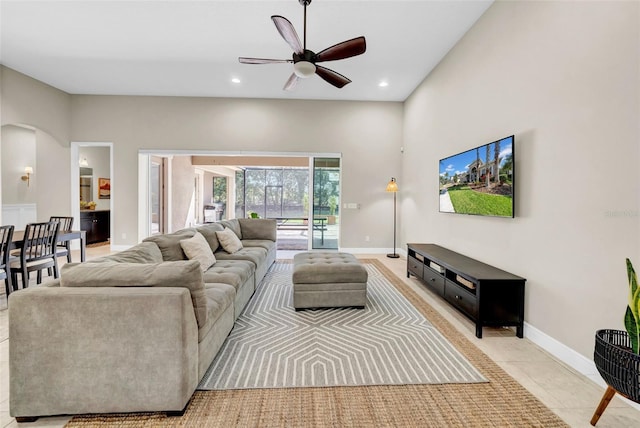 living area featuring arched walkways, light tile patterned floors, recessed lighting, a ceiling fan, and baseboards