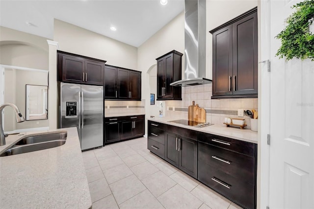 kitchen featuring black electric stovetop, a sink, stainless steel fridge with ice dispenser, wall chimney exhaust hood, and tasteful backsplash