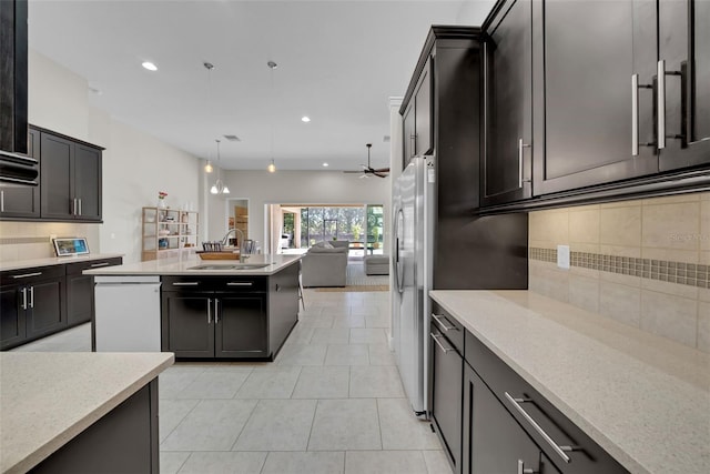 kitchen with hanging light fixtures, backsplash, open floor plan, white dishwasher, and a sink