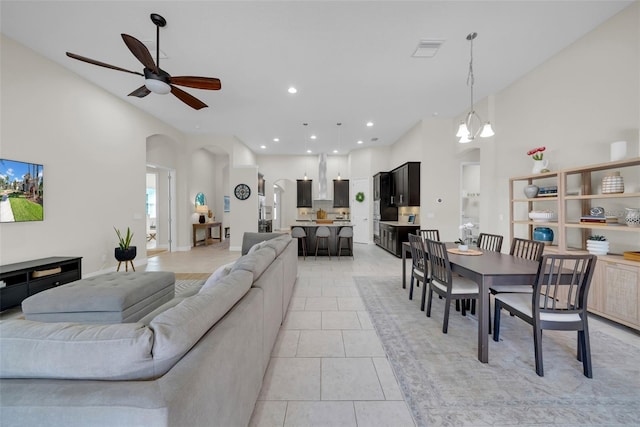 living area with a towering ceiling, visible vents, arched walkways, and light tile patterned flooring