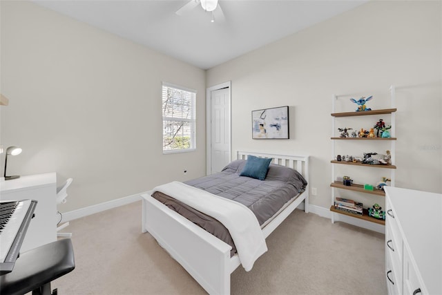 bedroom featuring baseboards, ceiling fan, a closet, and light colored carpet