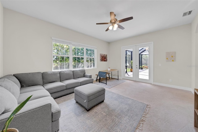 living area with french doors, visible vents, a ceiling fan, light carpet, and baseboards