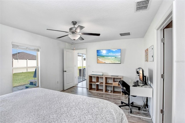 bedroom with a textured ceiling, wood finished floors, and visible vents